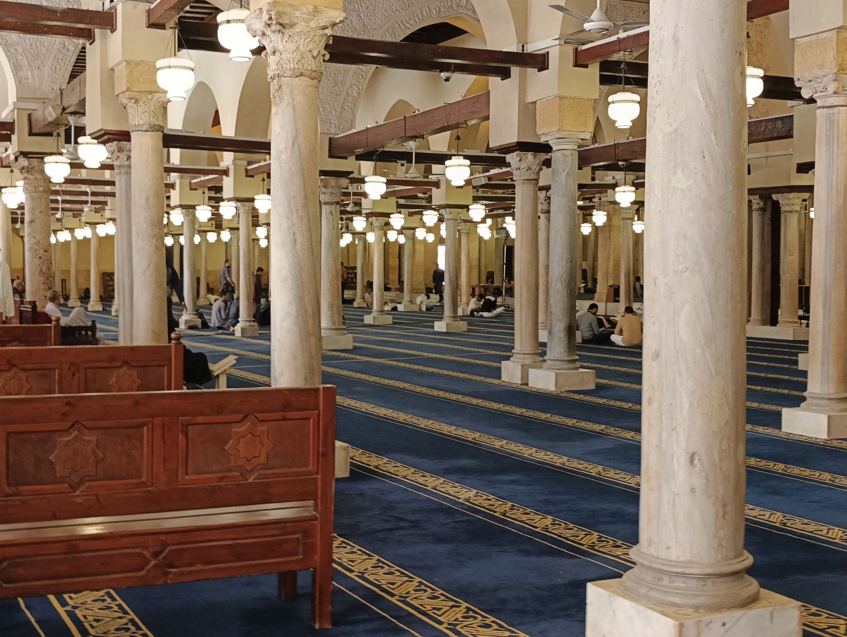 Interior of a historic mosque in Cairo Egypt with visitors observing quietly