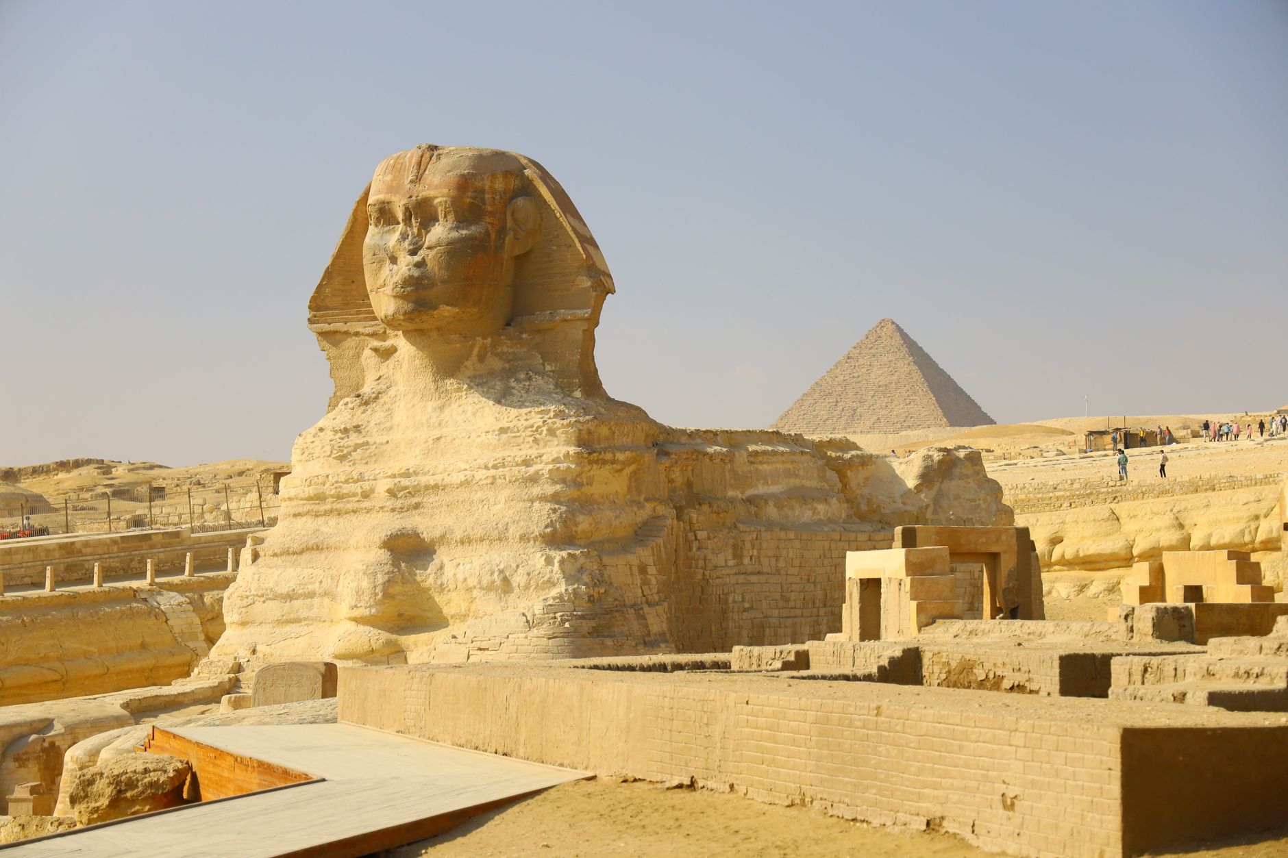 Pyramids of Giza History & Facts: What You Should Know 4 The Great Sphinx of Giza with a pyramid rising behind it under blue sky Egypt