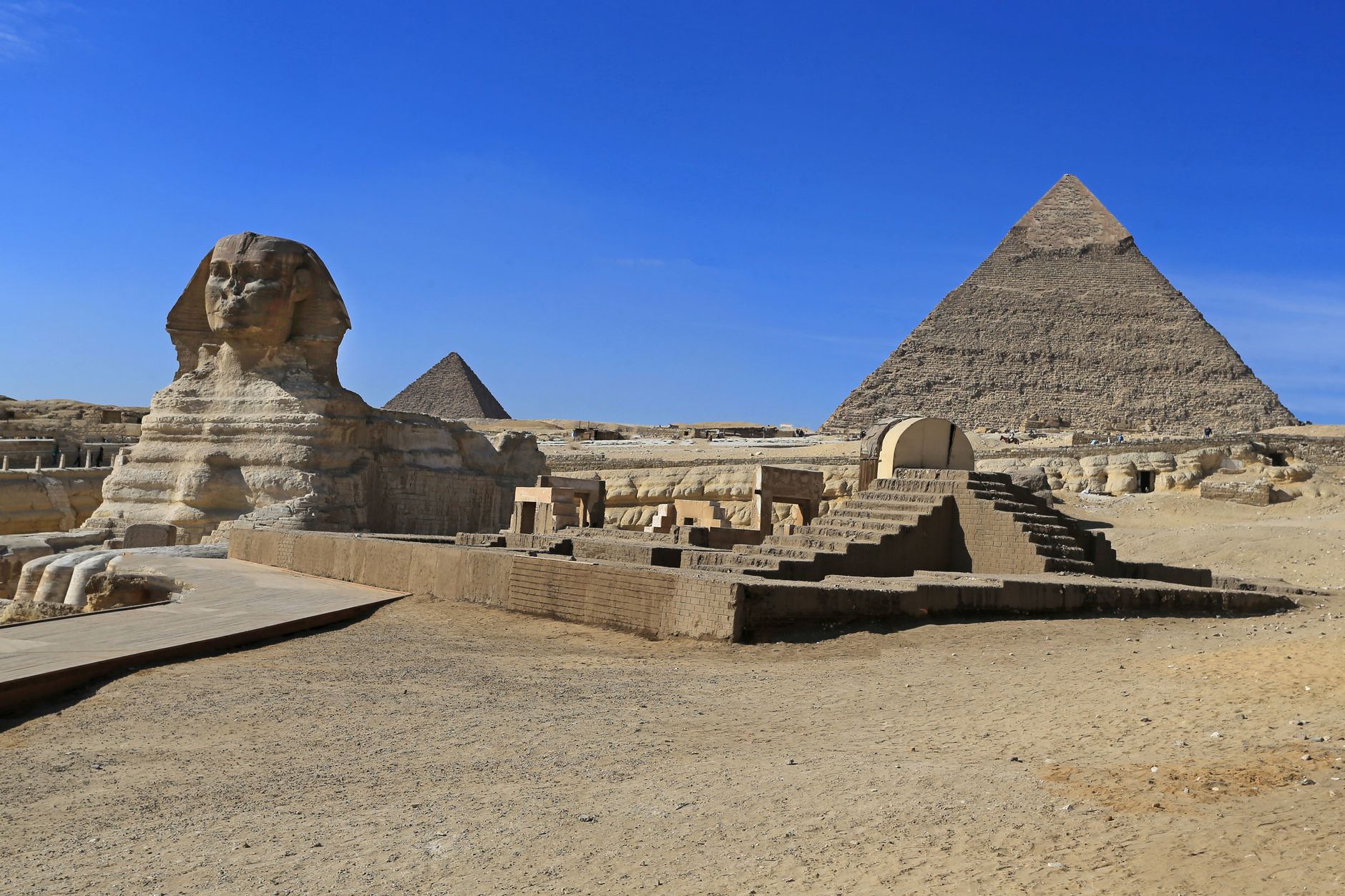 The Pyramids of Giza and the Great Sphinx under a clear blue sky on the edge of Cairo, Egypt