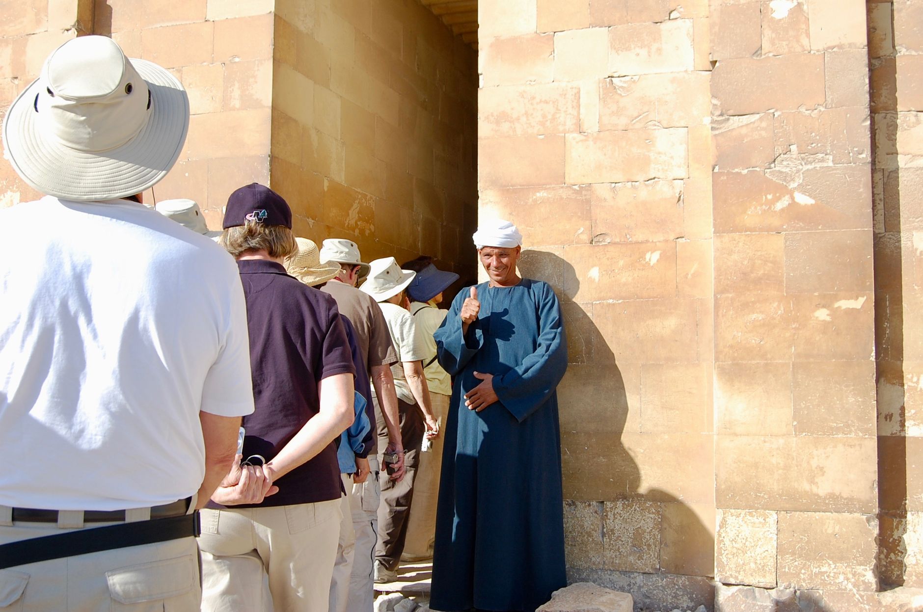 Egyptian tour guide with visitors at ancient site