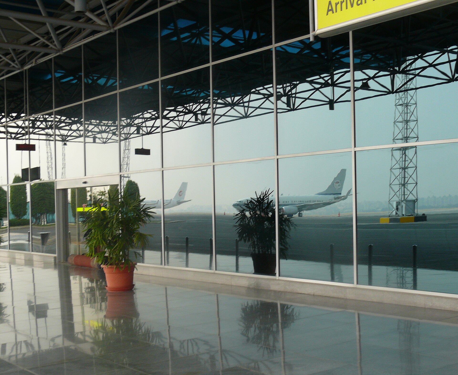 Egypt Visa on Arrival at Cairo Airport: Step by Step 3 The glass wall of an arrivals building at Cairo International Airport with an Arrival sign and aircraft reflected on the apron