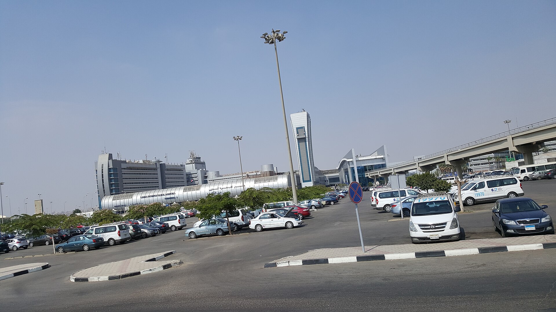 Sphinx International Airport and Cairo's Other Airports 5 The curved silver facade of Terminal 1 at Cairo International Airport seen across the car park, with taxis and minivans parked in front