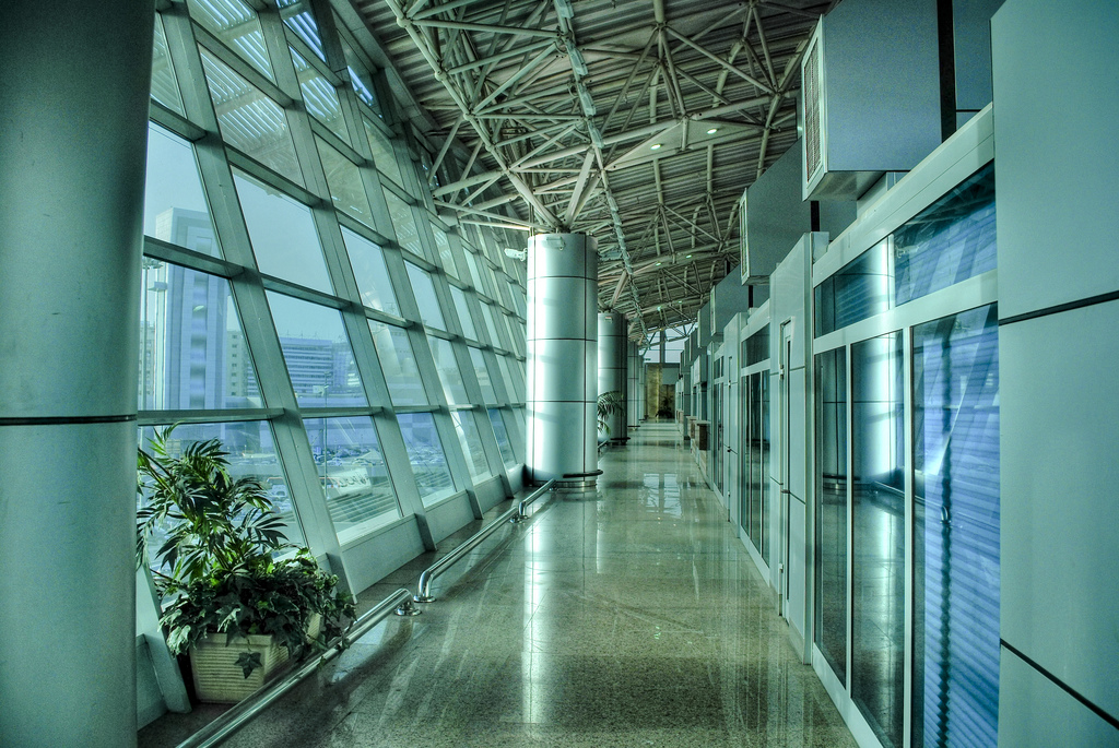 A long glass-walled corridor with a steel roof and polished floor inside Terminal 3 at Cairo International Airport