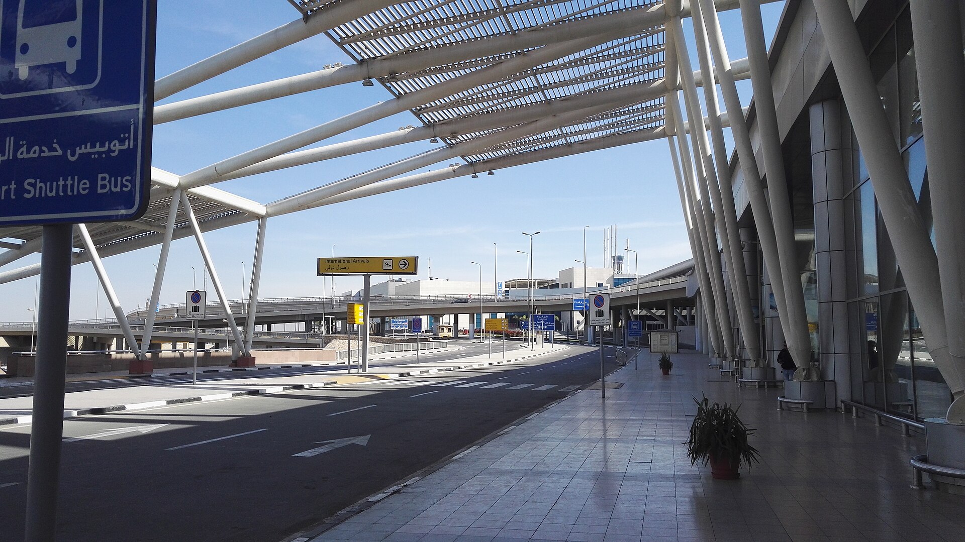 Egypt Visa on Arrival at Cairo Airport: Step by Step 5 The kerbside outside Terminal 3 at Cairo International Airport, with an International Arrivals sign and a blue Airport Shuttle Bus sign