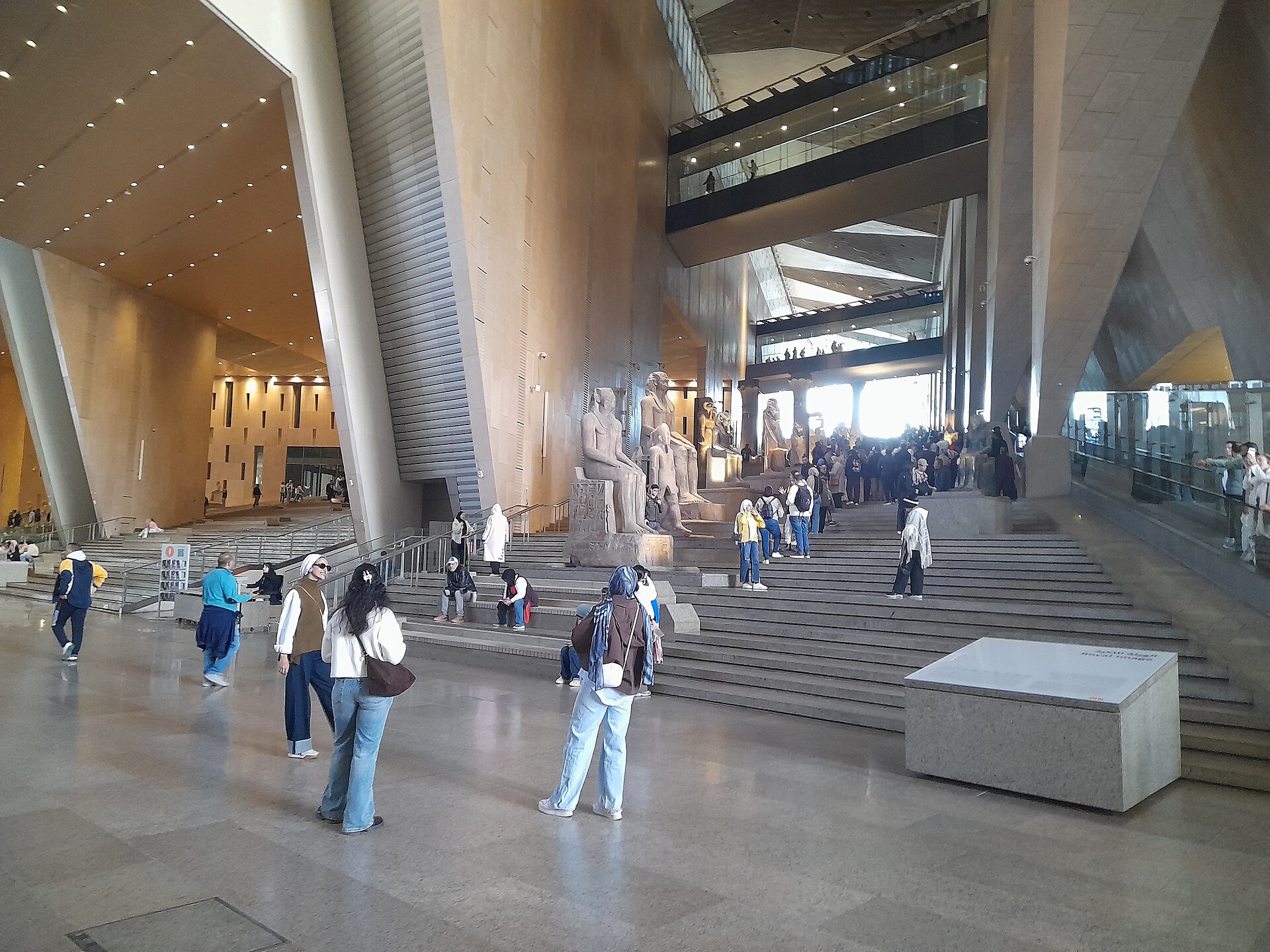 Grand Egyptian Museum with Kids: Family Visit Guide 2 Visitors and families in the Grand Hall of the Grand Egyptian Museum, with the Grand Staircase and colossal statues behind