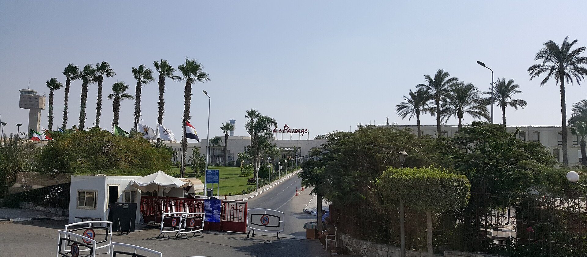 The palm-lined entrance drive of the Le Passage hotel beside Cairo International Airport, with the airport control tower on the left