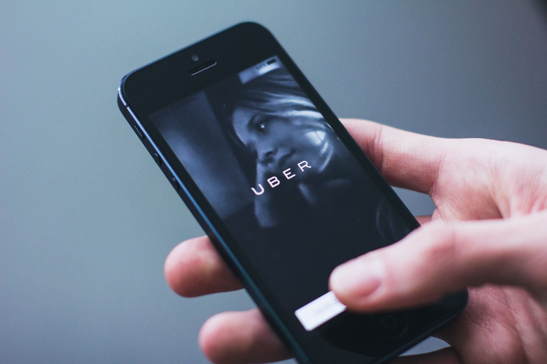 A hand holding a smartphone with the Uber ride-hailing app open on screen