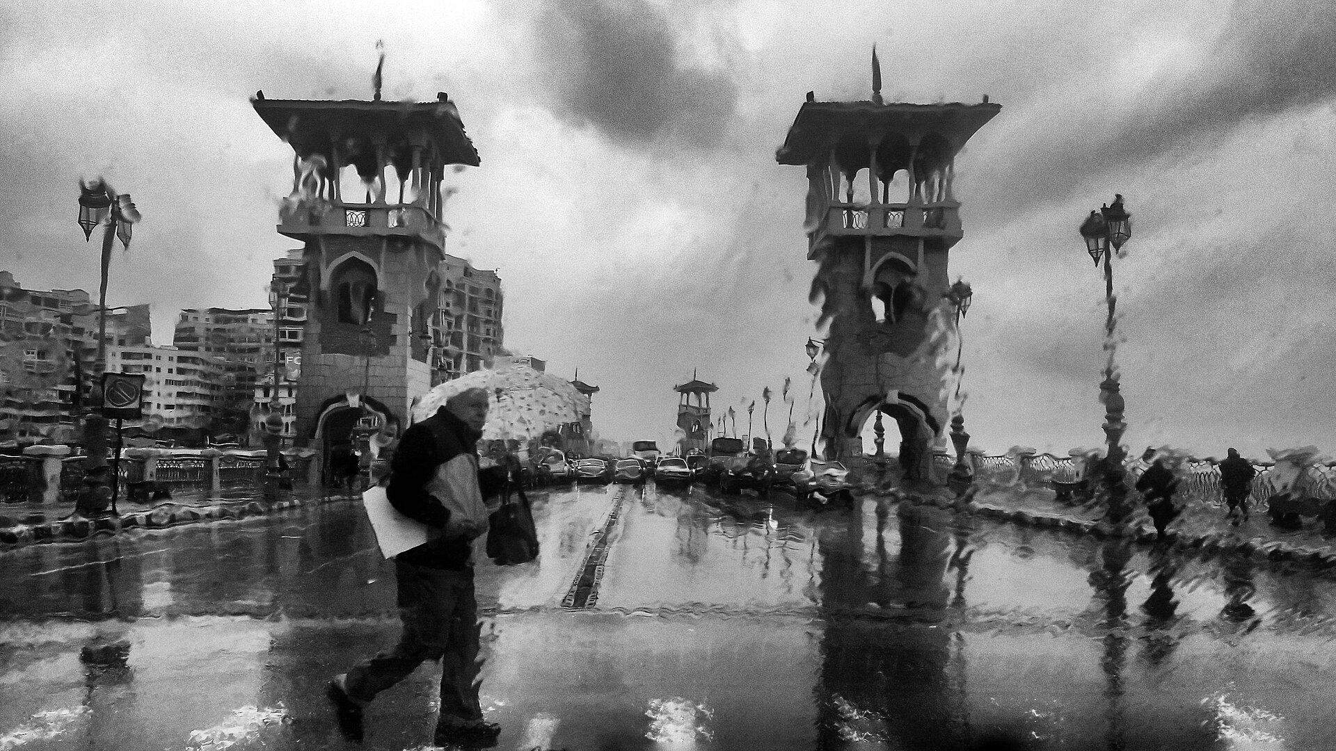 Cairo and Alexandria Itinerary: Five Days, Two Cities 6 Black-and-white view through a rain-streaked window of Stanley Bridge in Alexandria, with a man walking past under an umbrella