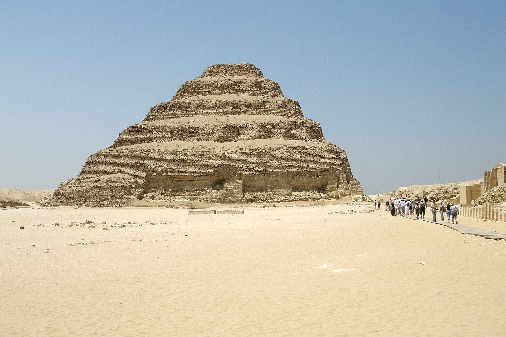 The Step Pyramid of Djoser at Saqqara rising from the desert with a small group of visitors on the path
