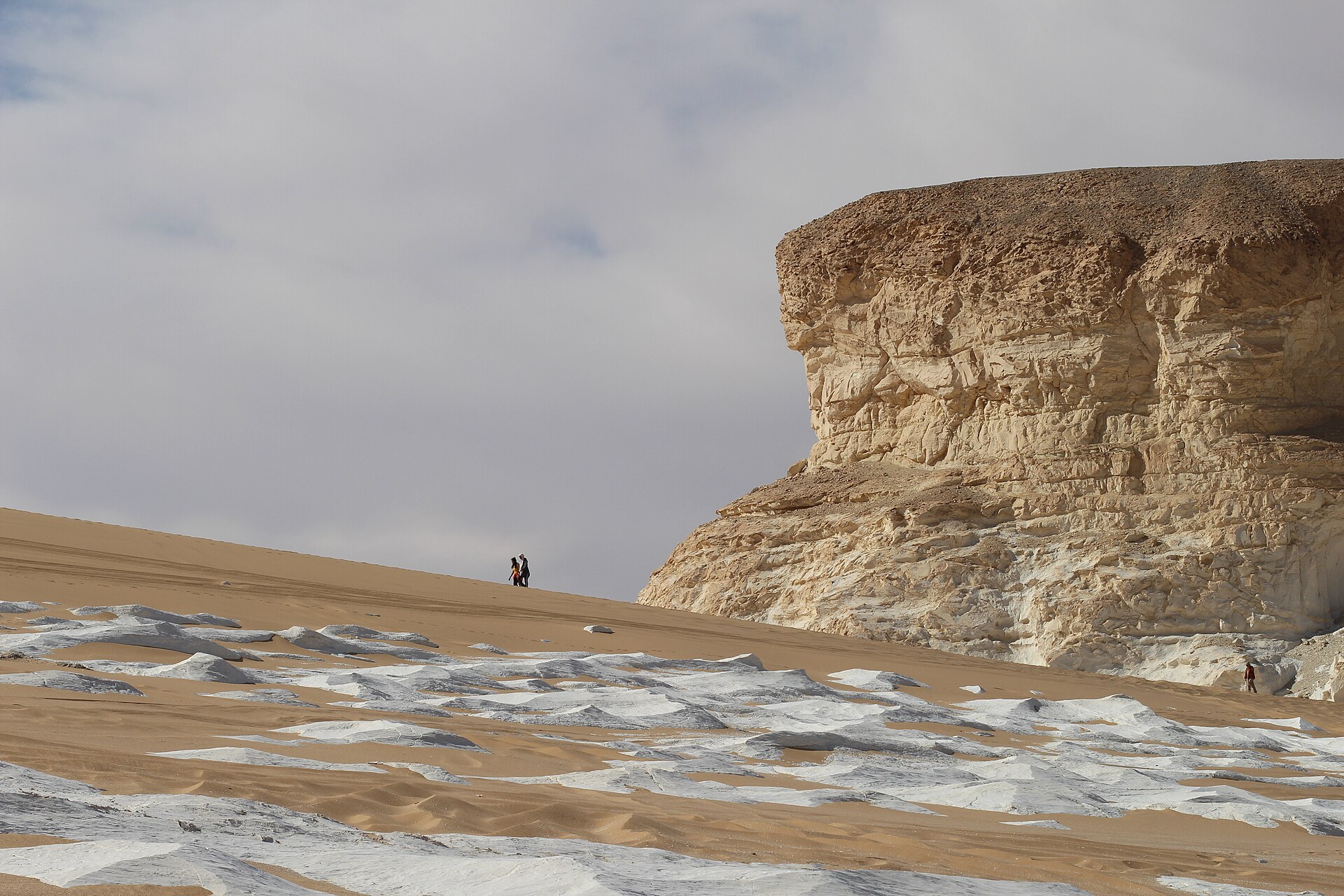 Chalk rock formations and sand in the White Desert National Park in Egypt with two figures on a dune