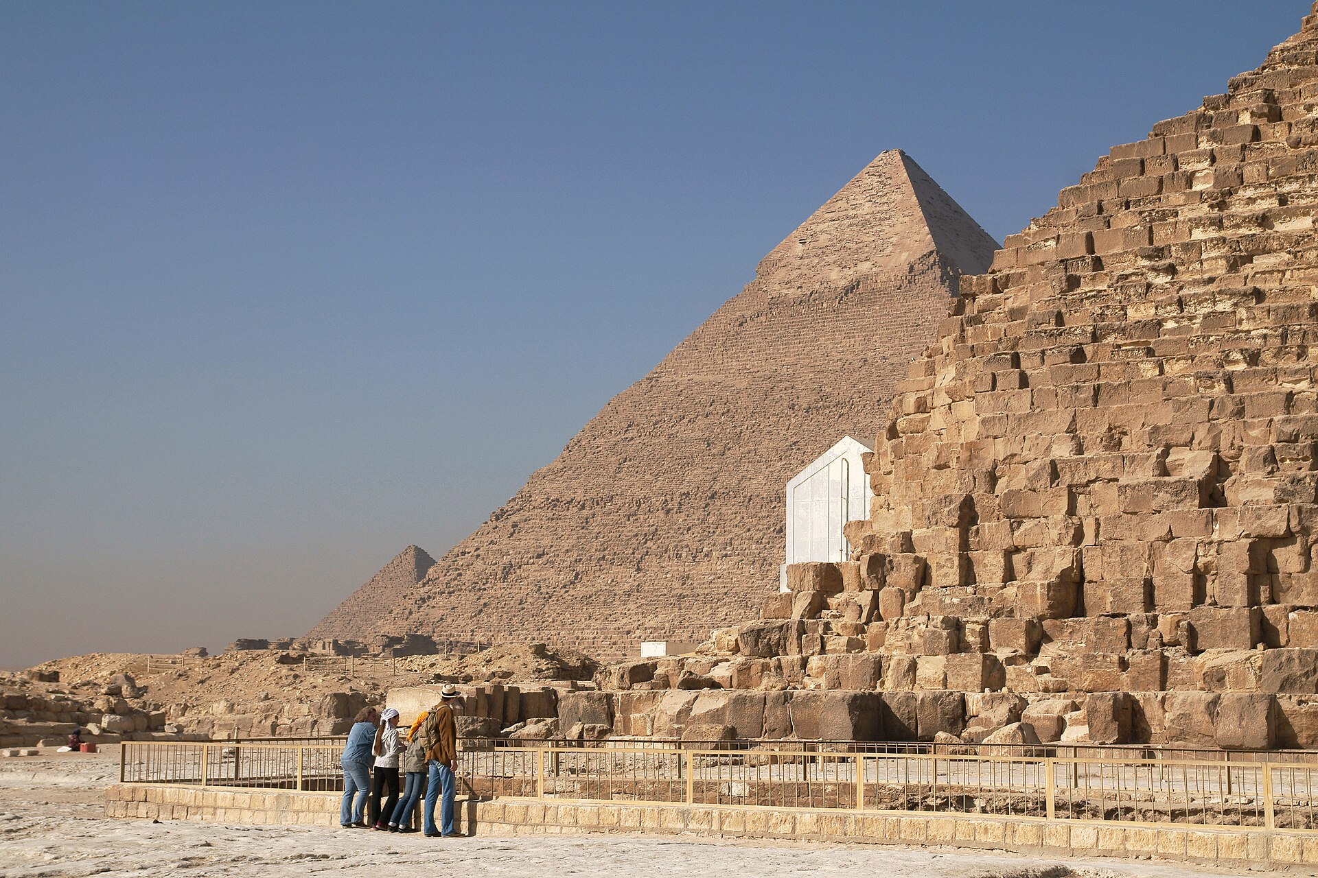 Cairo Tours and Tickets: How to Choose and Book 2 A small group of visitors at a railing beside the huge base blocks of the Great Pyramid, with the Pyramid of Khafre rising behind
